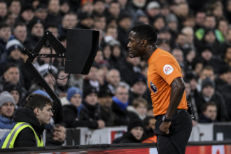 Referee reviewing VAR decision during football match 