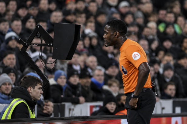 Referee reviewing VAR decision during football match 